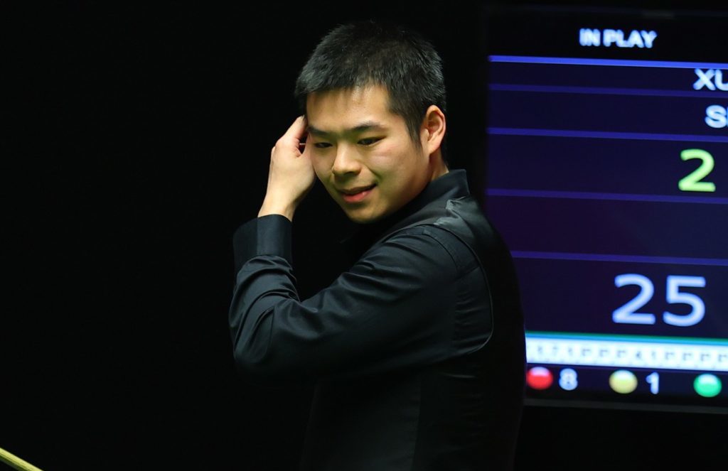 junger chinesischer Snookerspieler Pang Junxu steht mit Queue am Tisch und kratzt sich am Kopf