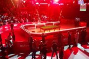 German Masters: TV-Tisch in der Arena in rotes Licht getaucht, drumherum stehen Menschen.