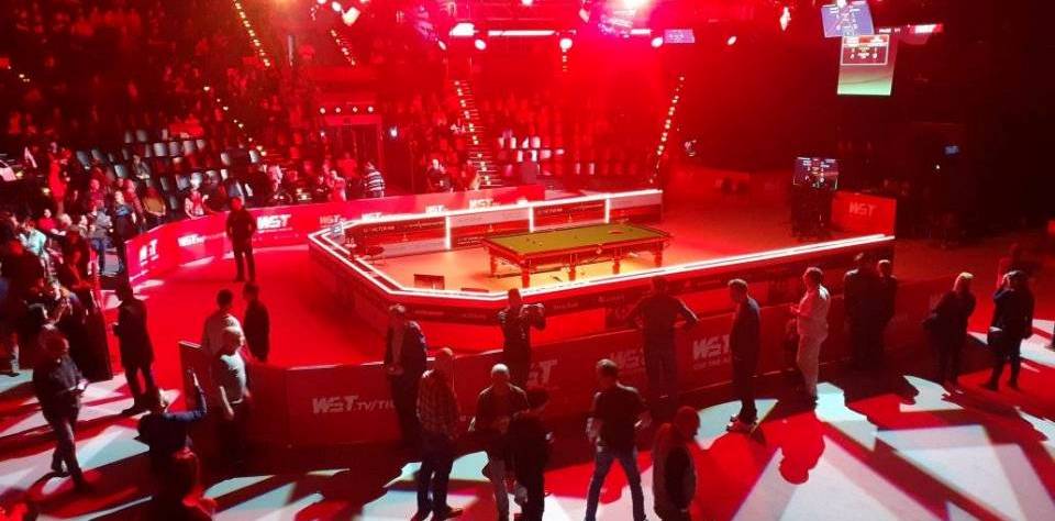 German Masters: TV-Tisch in der Arena in rotes Licht getaucht, drumherum stehen Menschen.