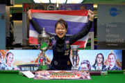 Weltmeisterin Baipat Siripaporn mit Thailand-Flagge und WM-Pokal am Snookertisch. Sie lacht über das ganze Gesicht.