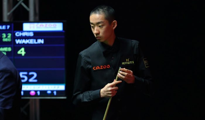 Judgement Day zum Einzug in die Endrunde der WM: Wu Yize, ein junger chinesischer Spieler mit rasiertem Schädel, hält ein Queue in der Hand und schaut auf den Tisch. Im Hintergrund ein Scoreboard mit dem Namen Chris Wakelin.