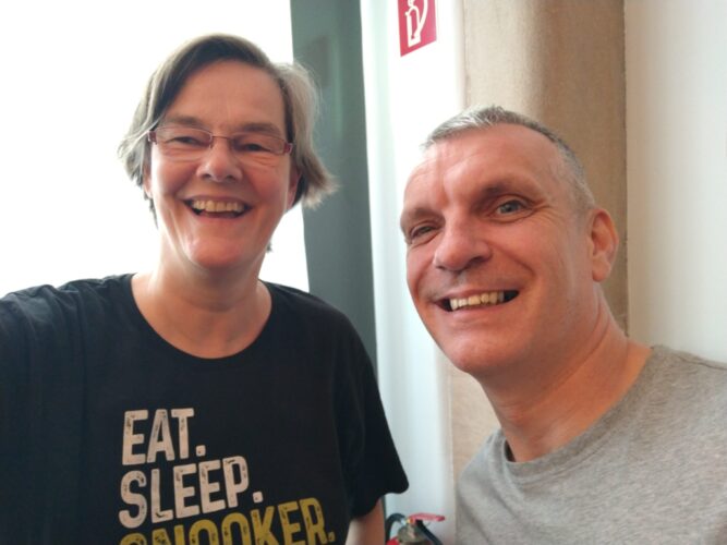 Selfie Mark Davis und ich, zwei Personen in den Fünfzigern mit T-Shirts, lachen in die Kamera.