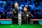 English Open 2023: Judd Trump und Zhang Anda mit der Glastrophäe geben sich vor dem Spiel die Hand am Snookertisch.