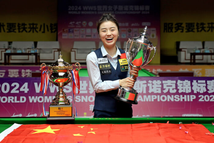 WM-Titel: Bai Yulu, eine junge Spielerin, hält lachend den WM-Pokal, neben ihr auf dem Rand eines Snookertisches die U21-Trophäe.