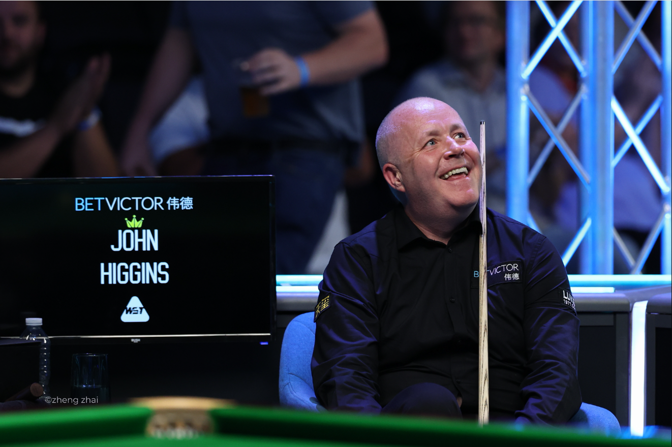 John Higgins mit einem breiten Lächeln auf seinem Platz