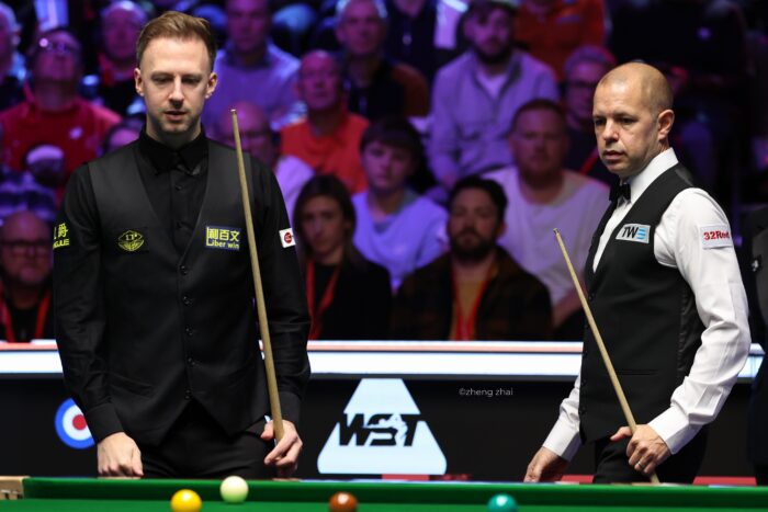 Judd Trump und Barry Hawkins an der Fußbande, beide den Blick auf den Tisch gerichtet.