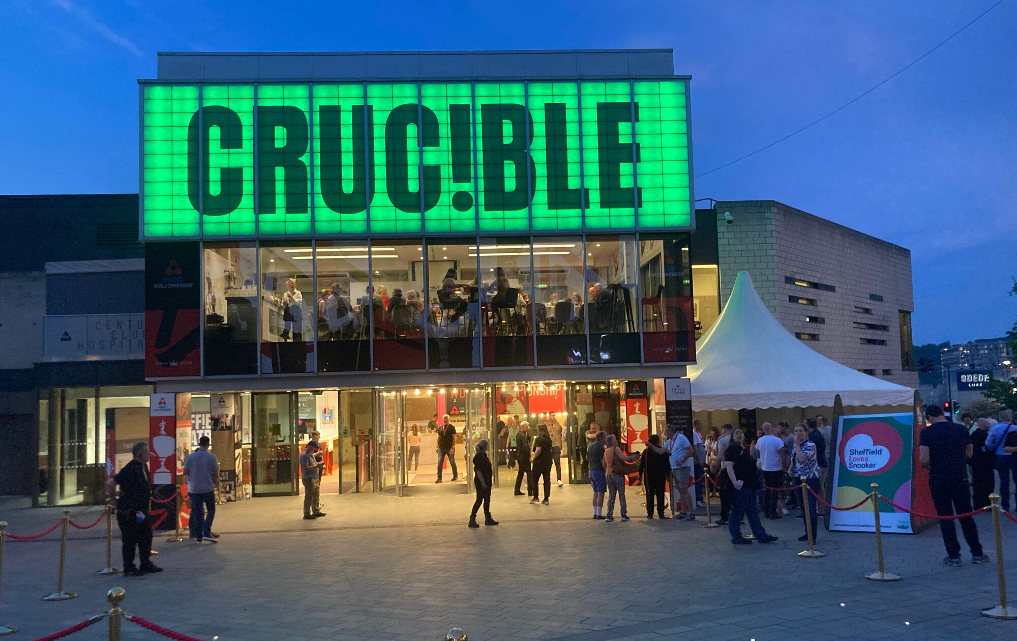 Das Crucible in der Abenddämmerung. Seitlich davor sind ein paar Leute versammelt.