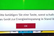 Foto einer Anzeige am Fernseher "Bitte betätigen Sie eine Taste, sonst schaltet das Gerät zur Energieeinsparung in Stand-by!"