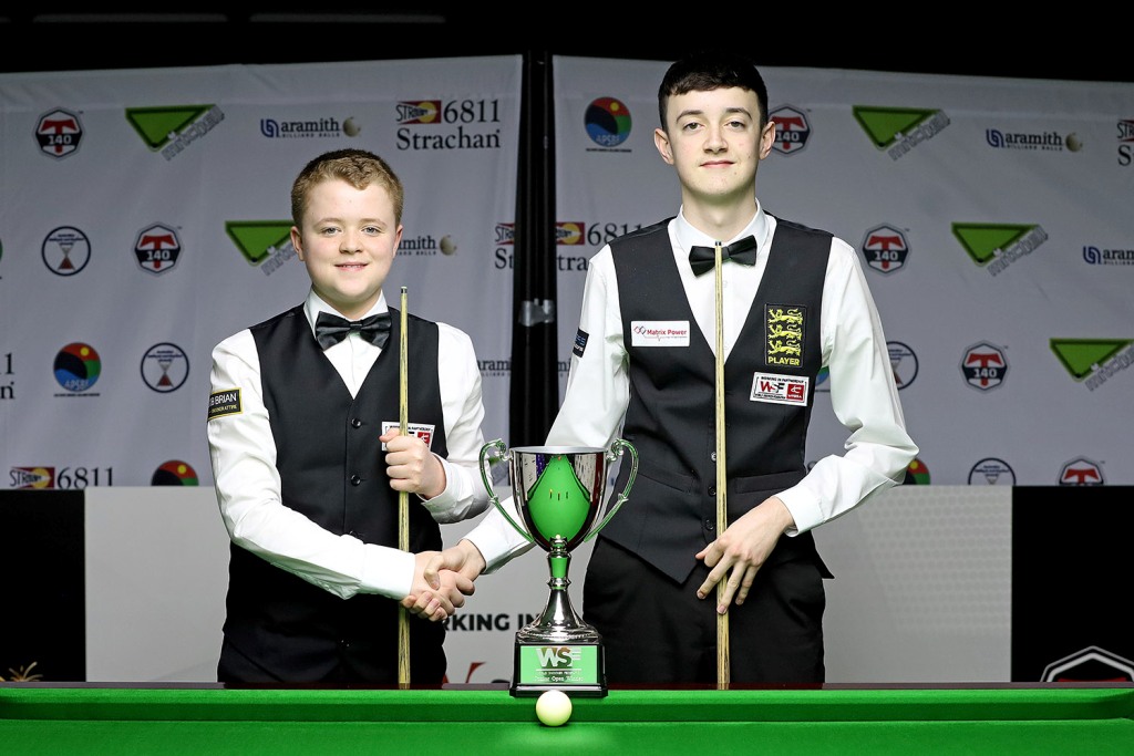 Stan Moody und Liam Pullen ein paar Jahre jünger als heute mit Handshake an einem Tisch mit kleinem Pokal.