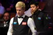 Pang Junxu bei seinem Spiel gegen Neil Robertson, der unscharf im Bildvordergrund zu sehen ist.