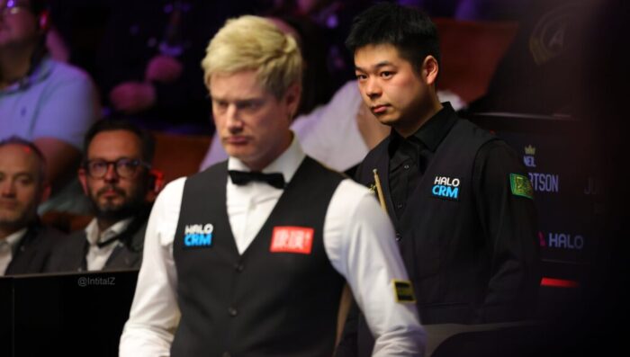 Pang Junxu bei seinem Spiel gegen Neil Robertson, der unscharf im Bildvordergrund zu sehen ist.