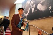 Zhao Xintong läuft vor seiner Titelverteidigung am Media Day mit dem WM-Pokal die Treppe im Crucible herunter.