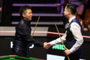 Xiao Guodong schüttelt dem Qualifikanten Zhou Yuelong die Hand. Zhou lächelt.