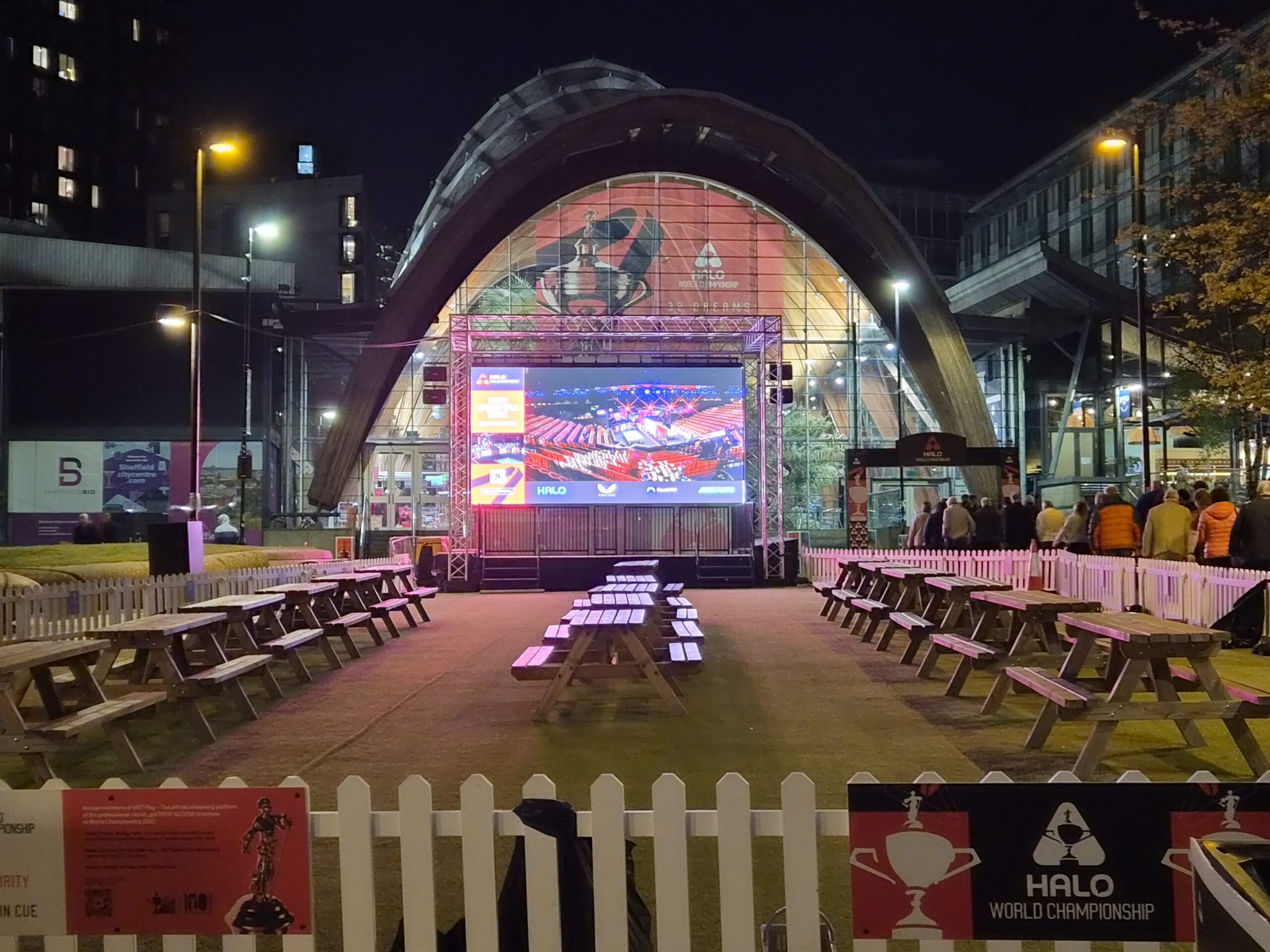 Public Viewing, leere Bänke, nachts. Die Leinwand zeigt noch das leere Crucible von innen.