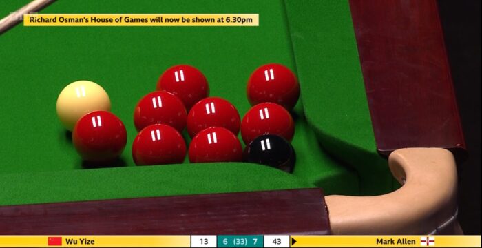 Beim Spielstand von 7 zu 6 für Mark Allen über Wu Yize steht es 43 zu 13 für Allen in Frame 14. Gezeigt ist eine Nahaufnahme der rechten Ecktasche an der Kopfbande, an die sich der Spielball sowie acht Rote kuscheln, der Eingang der Tasche wird dabei durch Schwarz blockiert. Oben im Bild sieht man einen Hinweis eingeblendet, dass sich die Ausstrahlung von Richard Osmans House of Games verzögert.