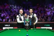 Shaun Murphy und Wu Yize vor dem Pokal der Weltmeisterschaft 2026. Hinter den beiden steht der Schiedsrichter Rob Spencer.